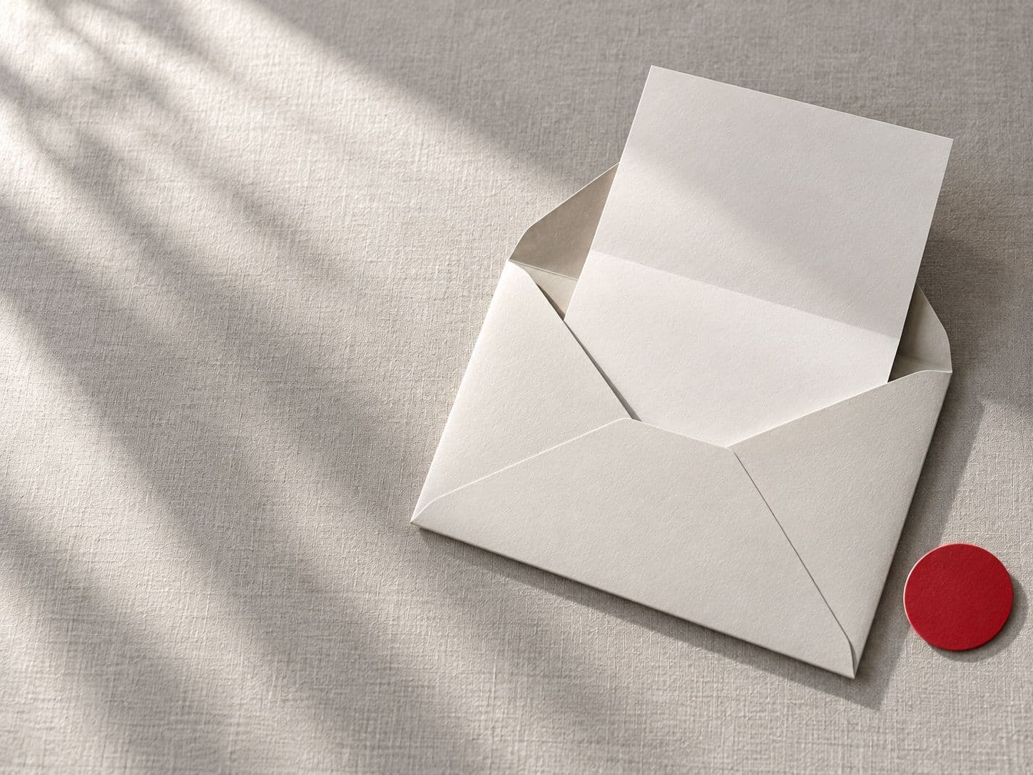 Open envelope with a blank letter and a red sticker on grey linen