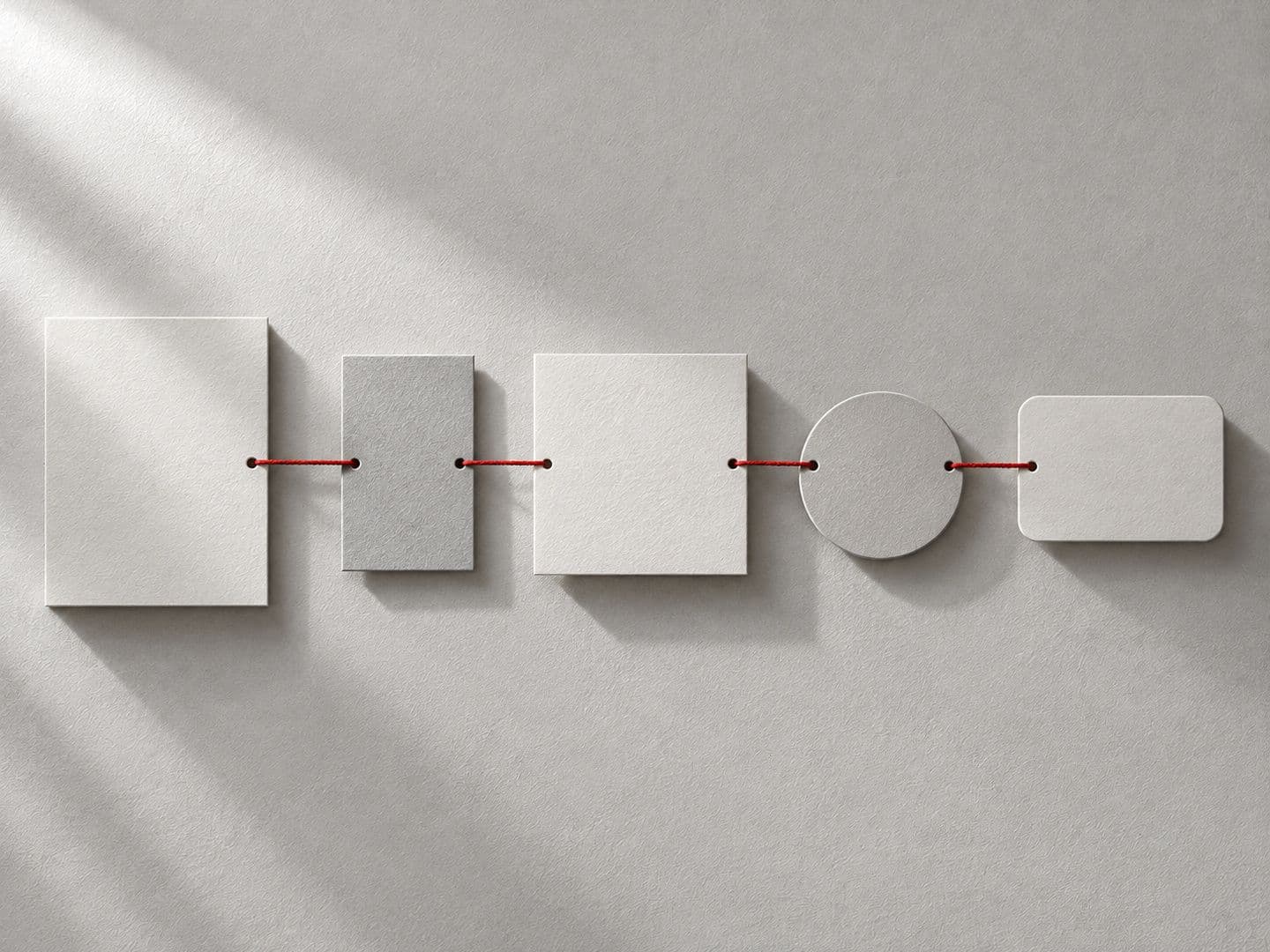 Paper shapes in a row joined by a red thread
