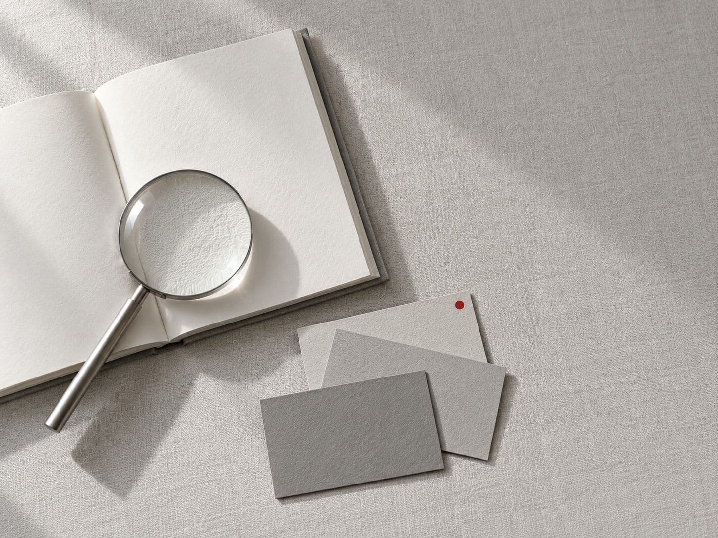 Open notebook, a magnifier and blank cards, one with a red dot